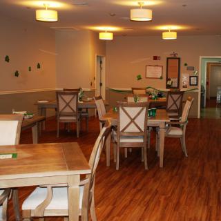 A cozy dining area with wooden tables and chairs, featuring soft lighting and a warm atmosphere.