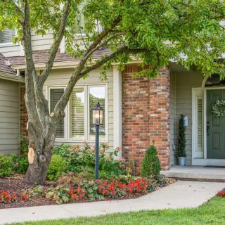 A charming house exterior with a landscaped front yard and a green door.