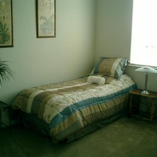 A simple and tidy bedroom with a single bed, side table, and lamp.
