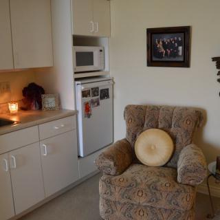 A cozy living space with a kitchenette, featuring an armchair and microwave.