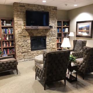 A cozy living room with a stone fireplace, bookshelves, and comfortable seating.