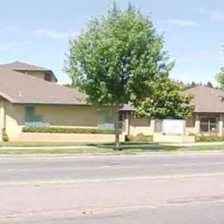 A suburban building with trees and a road in front.