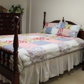 A cozy bedroom with a wooden bed frame and a colorful patchwork quilt.
