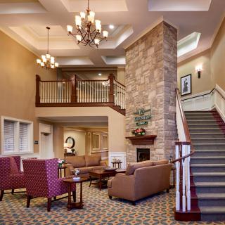 A spacious lobby with comfortable seating, a grand staircase, and an elegant chandelier.
