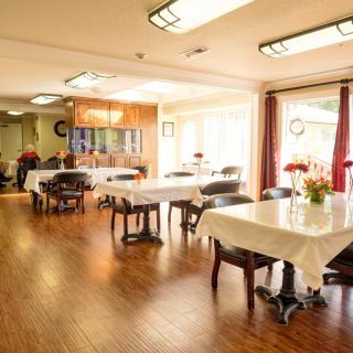 A bright dining room with neatly arranged tables and chairs, illuminated by natural sunlight.