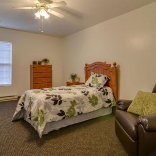 Cozy bedroom with a single bed, dresser, and armchair.