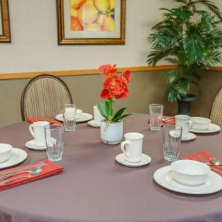 A neatly arranged dining table with place settings and a decorative flower centerpiece.