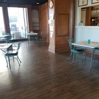 An empty restaurant dining area with tables and chairs on a wooden floor.