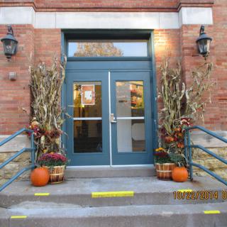 An entrance decorated for autumn with pumpkins and corn stalks.