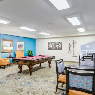 A spacious game room featuring a pool table, comfortable seating, and wall artwork.