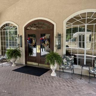 A welcoming building entrance with large windows, decorative plants, and seating.
