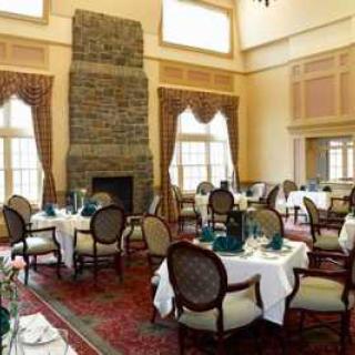 Elegant dining room with a large stone fireplace and set tables.