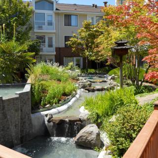 A beautifully landscaped garden with a water feature in front of an apartment building.
