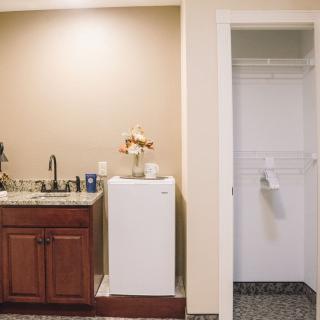 A kitchenette area with a sink, cabinet, refrigerator, and adjacent closet.
