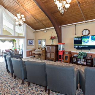 A spacious living room with a wooden ceiling, featuring comfortable seating and a television.