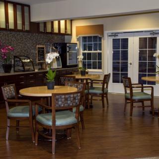 A modern kitchen and dining area with wooden tables, chairs, and decorative plants.