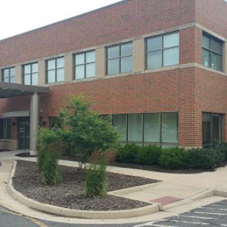 A modern brick building with multiple windows and landscaped surroundings.