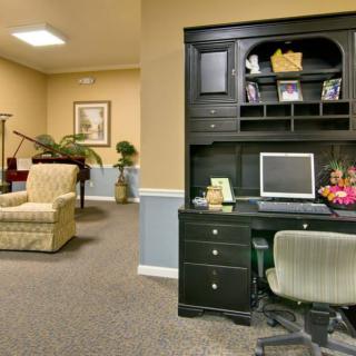 An office space with a desk and computer set up, adjacent to a lounge area with comfortable seating.