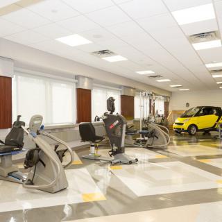 An indoor gym with various exercise equipment and a small yellow car.