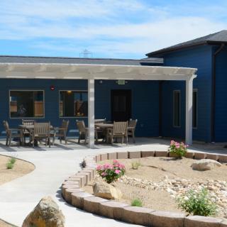 A modern building with an outdoor patio and desert landscaping.