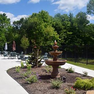 A beautifully landscaped garden with a fountain and a patio area on a sunny day.
