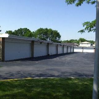 A row of garages in a residential area with a paved driveway.