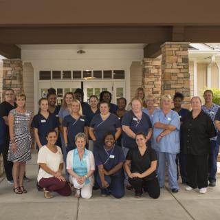 A diverse group of people in uniforms posing together outside a building.
