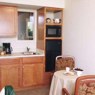A cozy kitchen and dining area featuring wooden cabinets, a small round table with chairs, and appliances such as a microwave and coffee maker.