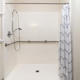An accessible shower with grab bars and a geometric-patterned curtain.