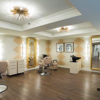 A luxurious and modern salon interior featuring stylish chairs, large mirrors, and elegant lighting.