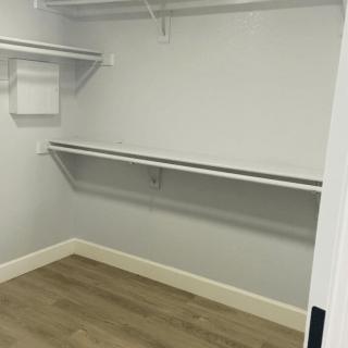 An empty closet with shelves and a wooden floor, ready for organization.