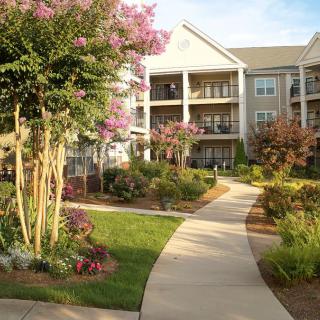 A scenic view of an apartment complex with landscaped gardens and blooming flowers.