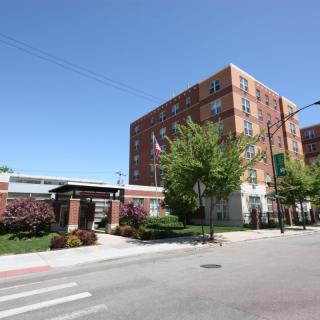 A brick building in an urban setting with trees and a crosswalk.