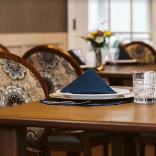 A neatly set dining table with a folded napkin, glass, and plate in a restaurant setting.