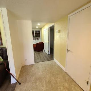 A view of a hallway leading into a kitchen area with tile and wooden flooring, and visible doors.