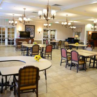 A spacious dining hall with chandeliers and floral arrangements on the tables.