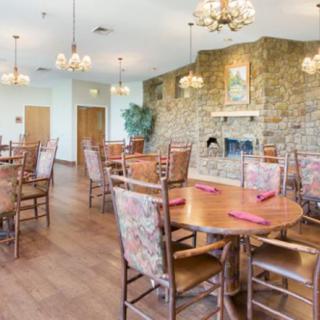 A cozy dining room with wooden tables, chairs, and a stone fireplace.