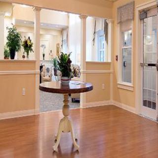 A welcoming entrance with a round table and plants on a wooden floor.