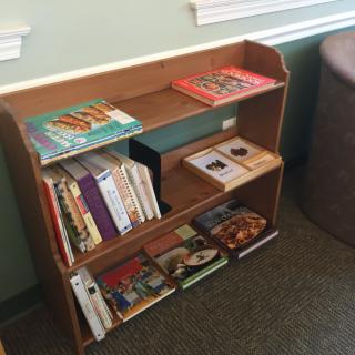 A small wooden bookshelf filled with various books in a library setting.