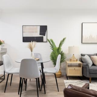 A modern and minimalist living room with a dining area featuring stylish furniture and greenery.