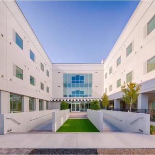 A modern architectural building featuring a spacious courtyard and lush greenery.