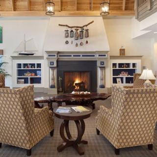 A cozy living room with a fireplace, armchairs, and bookshelves.
