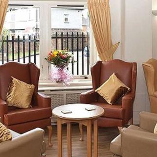 A cozy living room with comfortable chairs and a small table, decorated with flowers.
