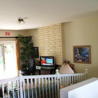 A cozy living room with a television, couch, and decor including a painting and lamp.