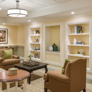A cozy living room with comfortable seating, shelves displaying decor, and warm lighting.