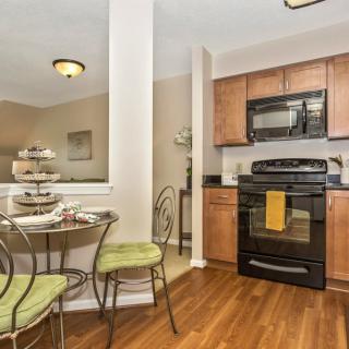 A modern kitchen with a small dining table set, featuring wooden floors and contemporary appliances.
