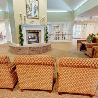 A cozy living room with patterned chairs facing a fireplace.