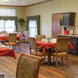 A cozy dining room with red tablecloths and wooden flooring, ready for guests.