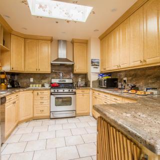 A modern kitchen with wooden cabinets and granite countertops, featuring stainless steel appliances.