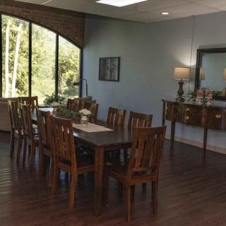 A well-lit dining room with a wooden table set and large windows offering a view of the outdoors.